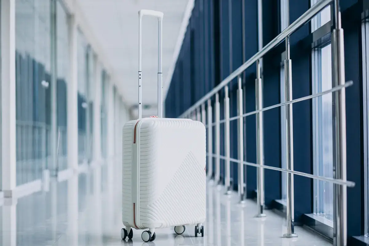 A white suitcase alone in a glass airport corridor