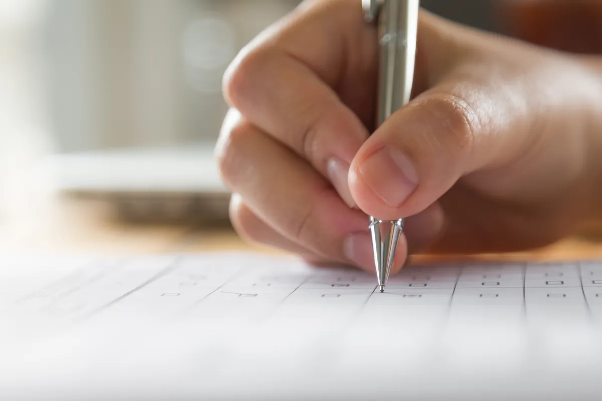 Gros plan sur une main qui écrit au stylo sur une feuille