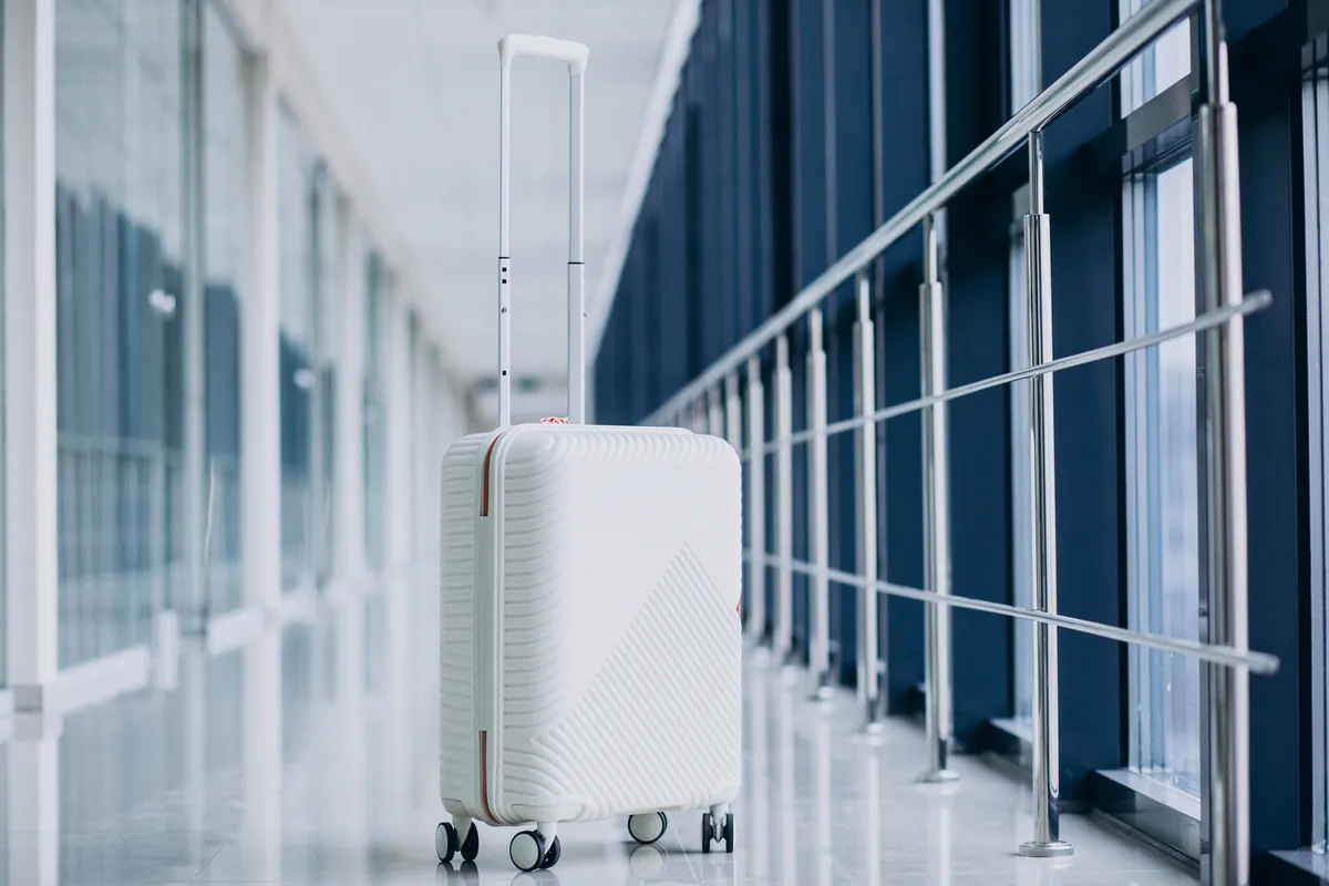 Une valise blanche seule dans un couloir vitré d'aéroport