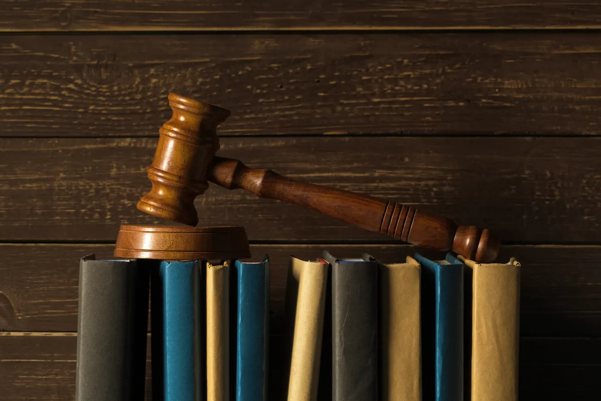Un marteau de juge posé sur une rangée de livres de droit